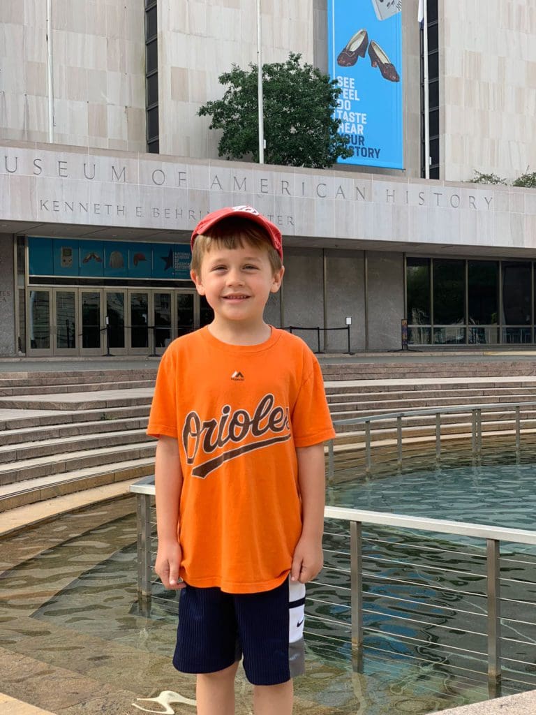 A young boy stands outside the entrance to the Smithsonian National Museum of American History.