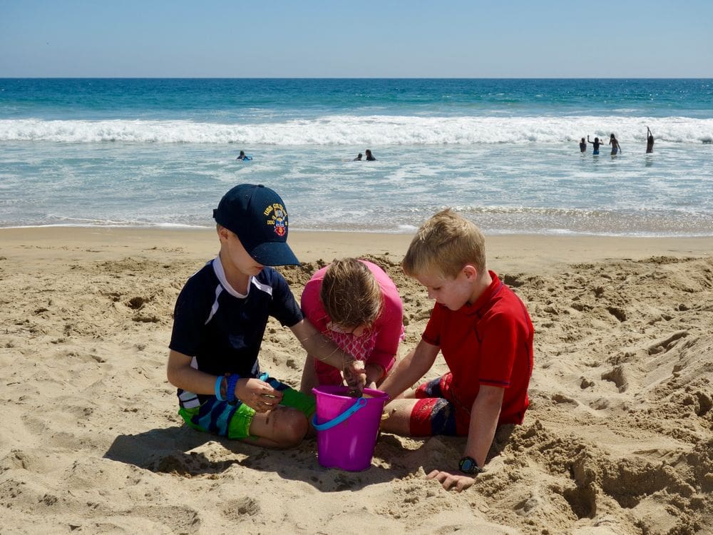 Three kids play in the sand while exploring San Diego, one of the top places in travel in 2023 with kids.