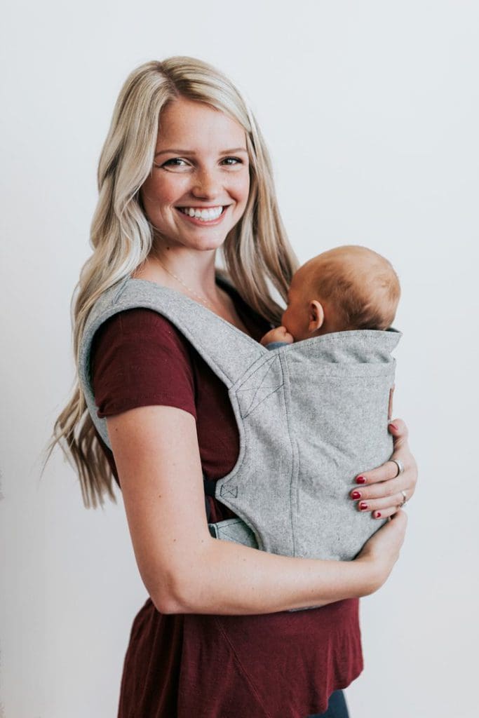A mom holds her infant in a front carrier by Happy Baby Carrier, one of the best baby carriers for travel.