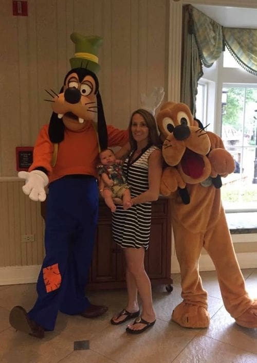 A mom and her infant son stand with Goofy and Pluto at Disney's Port Orleans - Riverside Resort, one of the best Disney moderate resorts for families.