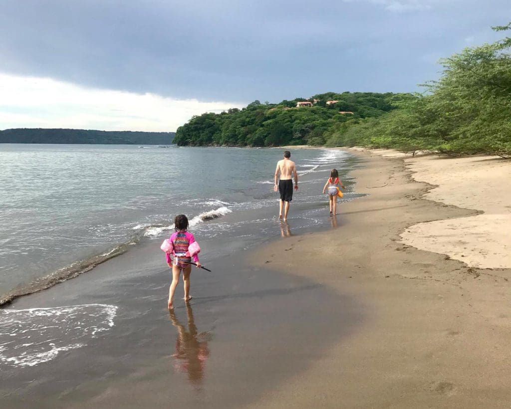 Three kids in bathing suits walk down Playa Panama in Costa Rica.