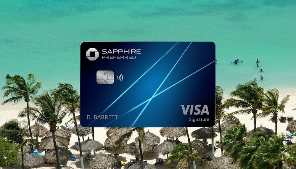 A close up of the Visa Chase Sapphire Preferred credit card, nestled on a background of a palm tree and oceanside setting.