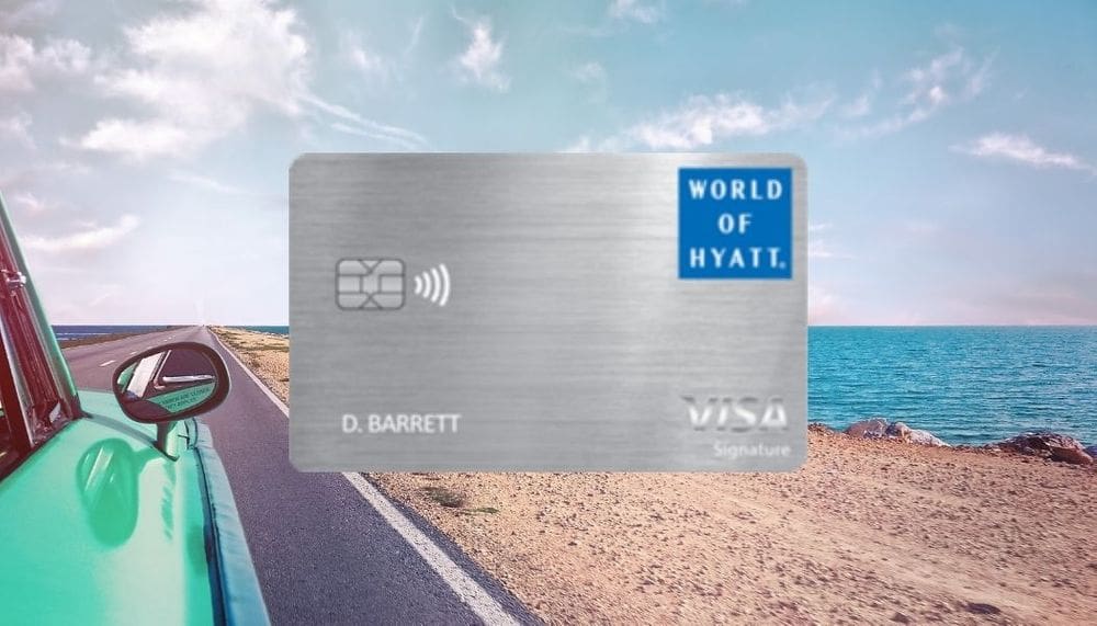 A close up of the Visa World of Hyatt credit card, nestled on a background of a green car on a road with a seaside view. It is one of best hotel credit cards for families