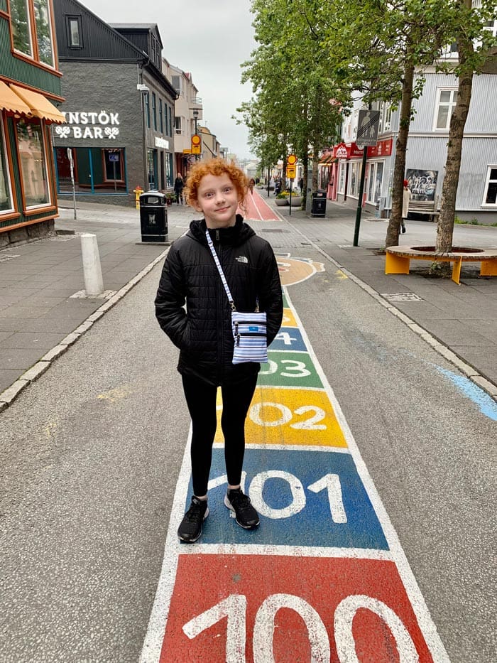 A young girl stands on a colorful street in Reykjavik. 