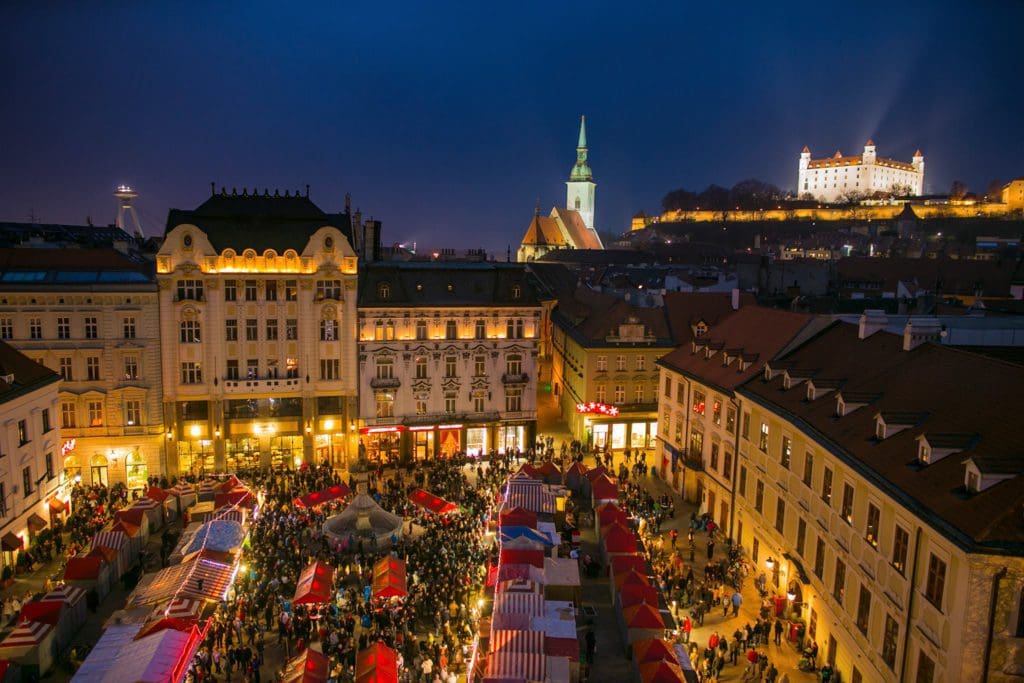 An aerial view of the well-lit square in Bratislava, featuring a courtyard full of stalls and people.