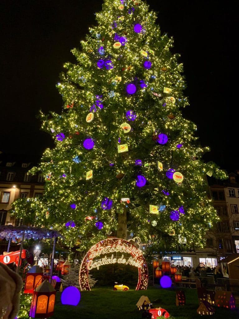 A large, decorated Christmas tree at the Strasbourg Christmas Market at night.