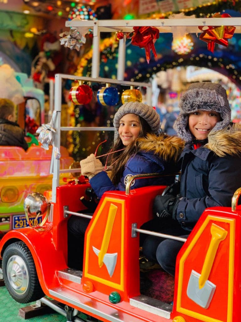 Two kids ride an amusement car at a Christmas market in France.
