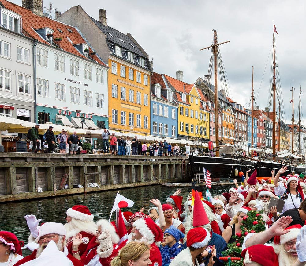 A boat full of Santas in a float heading down the river near in Nyhavn, a neighborhood in Copenhagen.