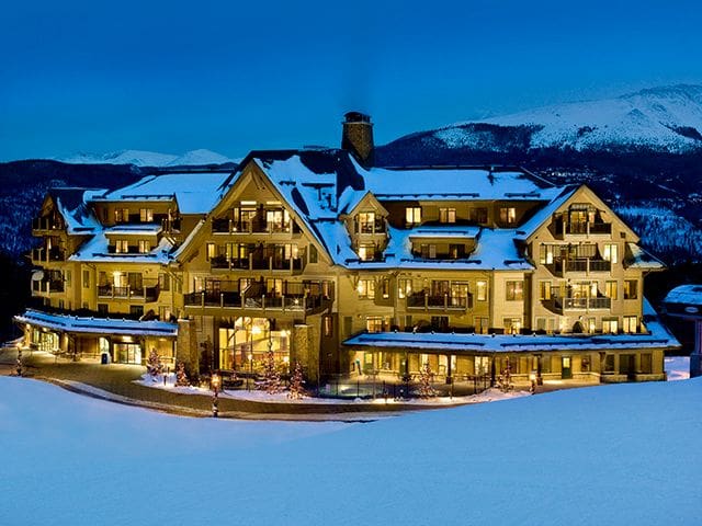 The front of Crystal Peak Lodge, covered in snow and lit up at night.
