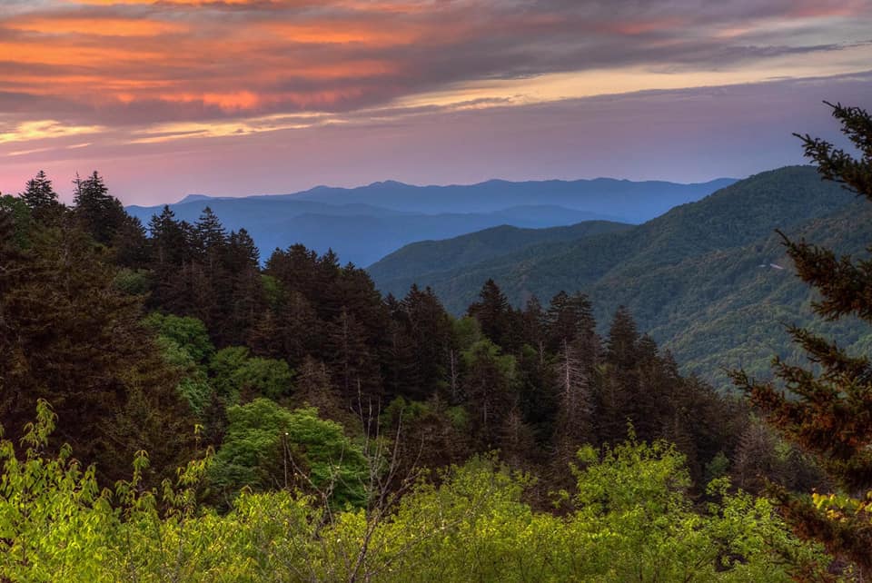 A stunning sunrise over the Smoky Mountains at Clingman's Dome, featuring hues of orange, pink, and blue.