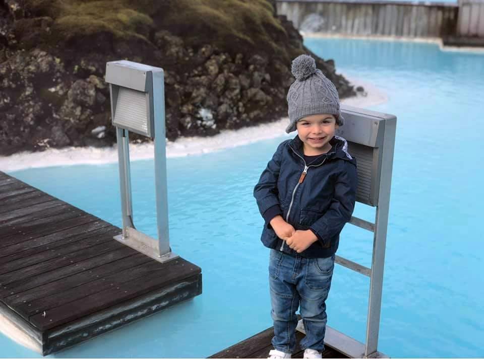 A young boy stands on the dock at the Blue Lagoon in Iceland, one of the best mild weather European destinations for a family summer vacation.