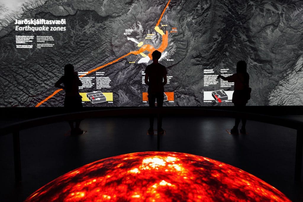 Three kids read a large display at the Lava Centre in Iceland.