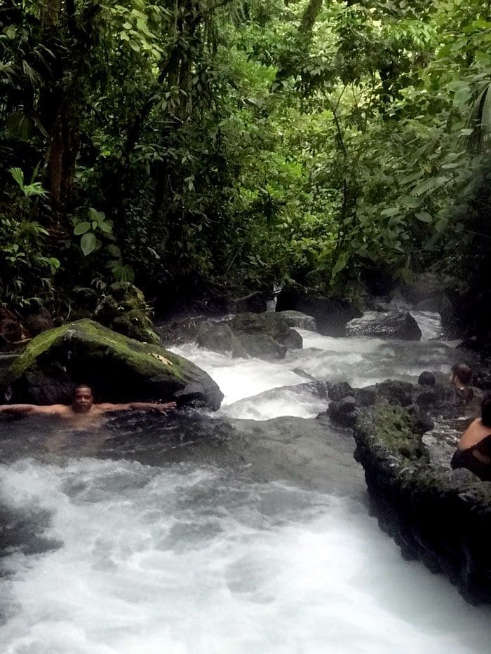 Dad and daughter relax in Rio Chollin in Costa Rica, surrounded by lush greens.