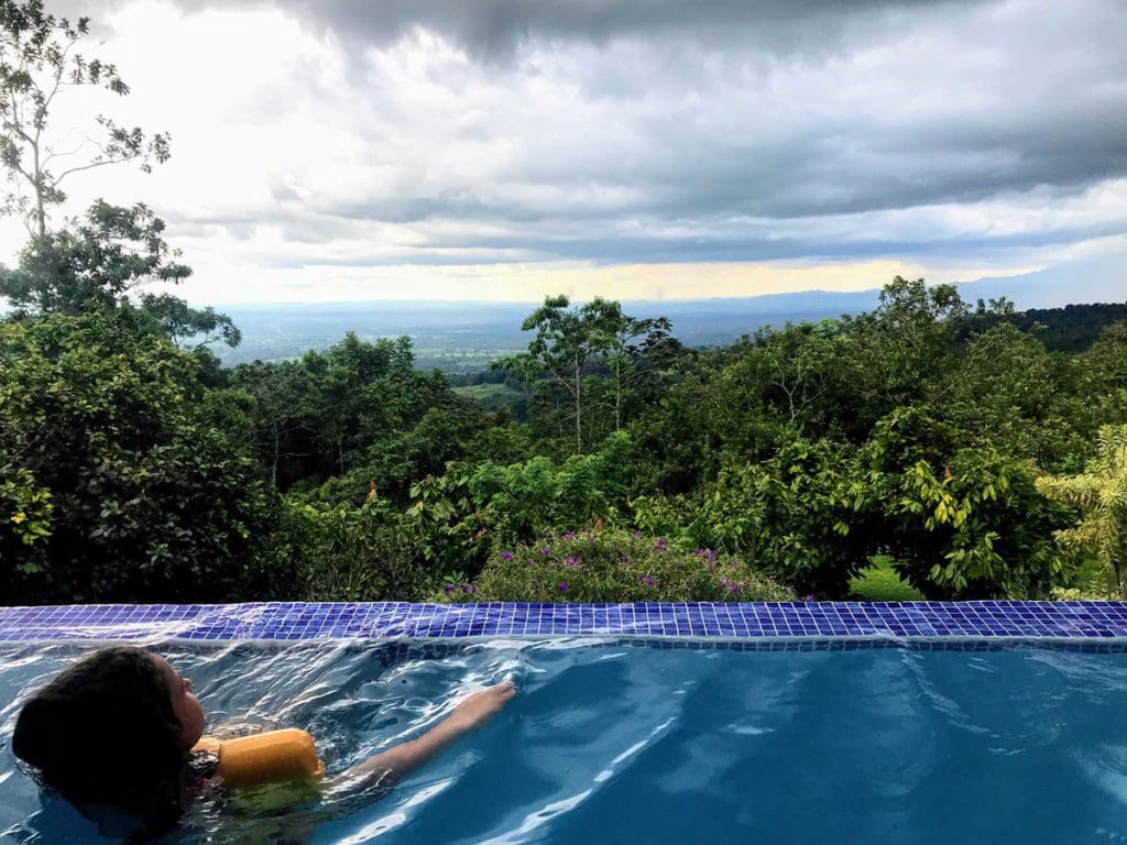 A young child relaxes in a plunge pool overlooking the Costa Rican jungle.