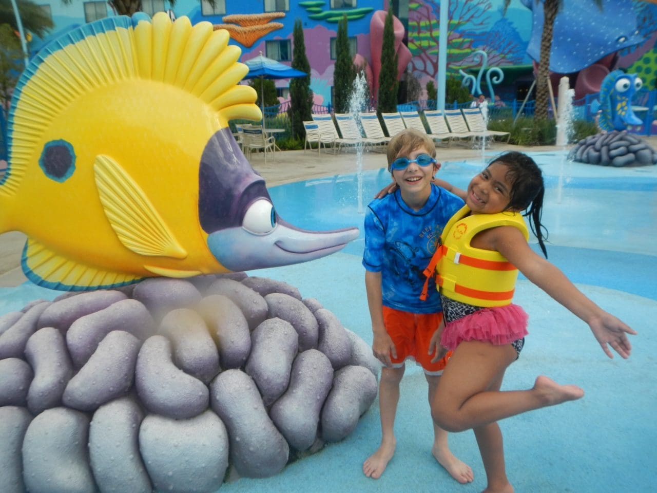 A brother and sister stand together by a large animated fish at Disney's Art of Animation Resort.