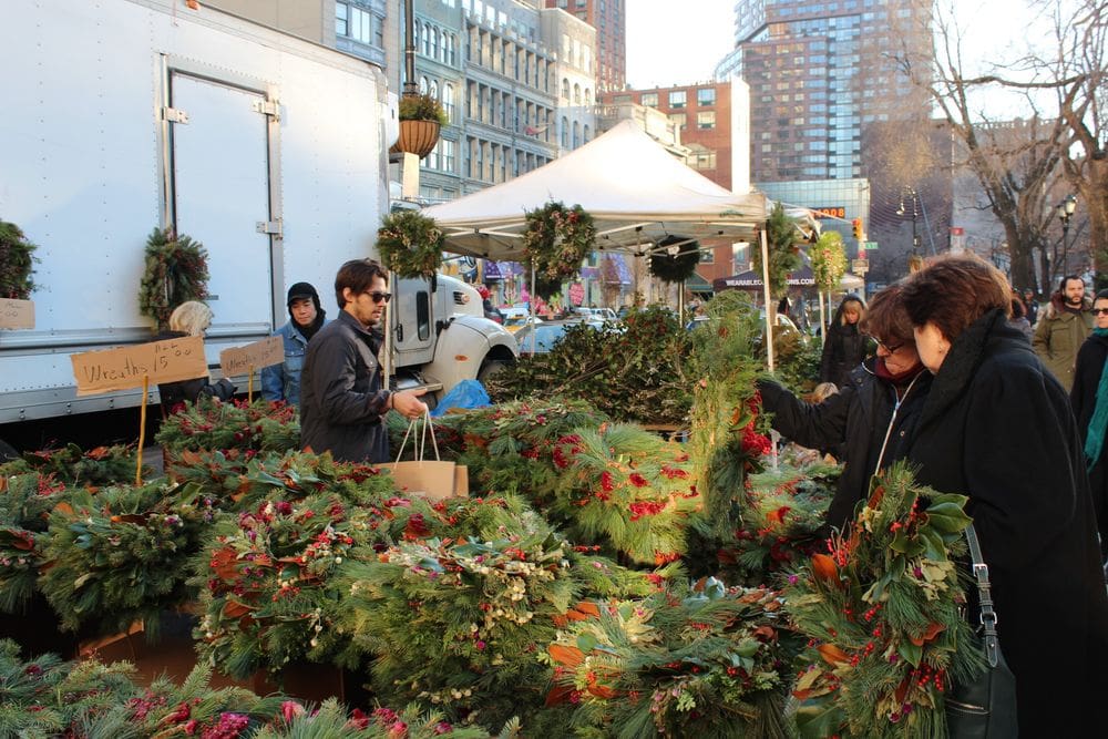 A few people look at a stall selling Christmas wreaths at the Union Square Holiday Market.