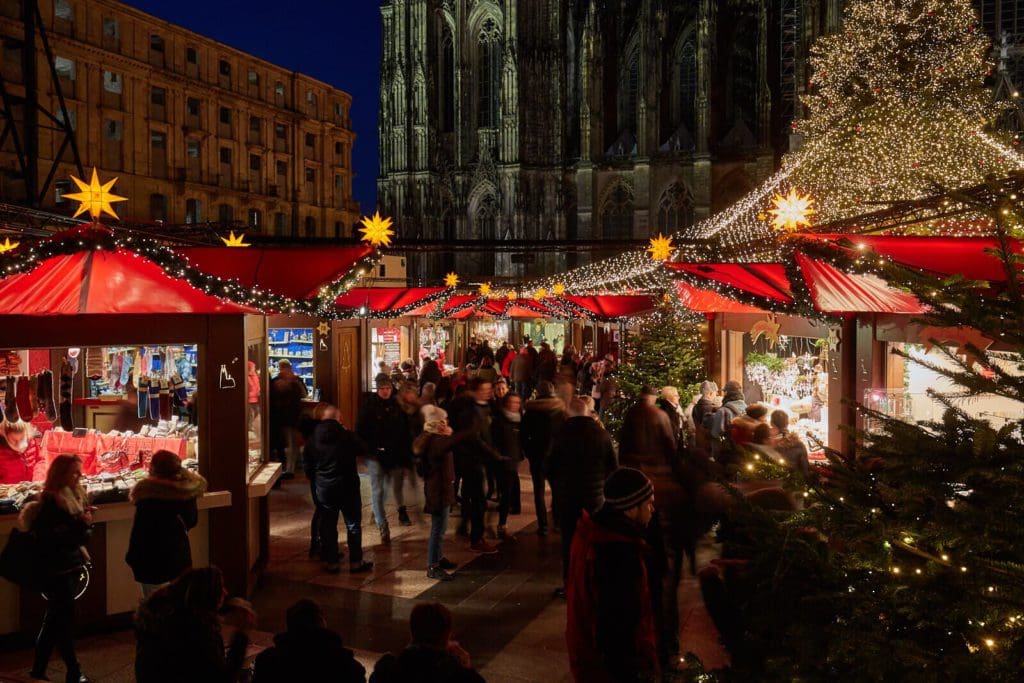 People mill about the stands, lit up at night, at the Vienna Christmas Market.