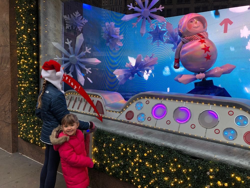 A mom and her daughter marvel at a Christmas window display in NYC.