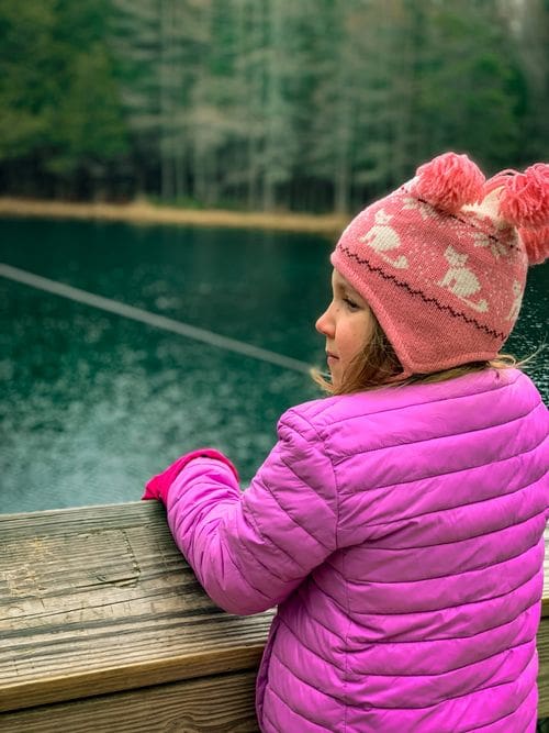 A girl looks over the raft ledge at the turquoise waters of Kitch-iti-kipi.