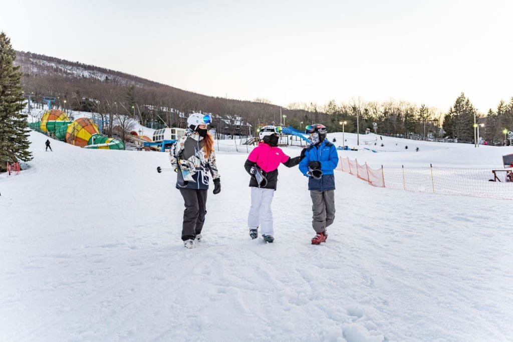 Three skiers walk across the snow toward the lift at the Camelback Resort and Indoor Water Park.