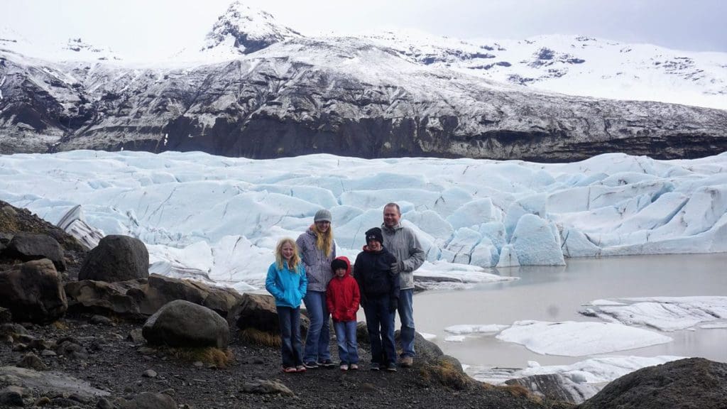 A family of five stands in front of a glacier in Iceland.