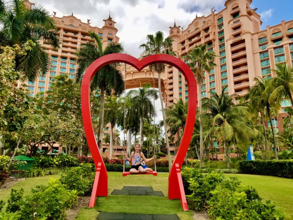 A young girl swings on the iconic heart swing at The Royal, one of the best hotels in the Bahamas for kids.