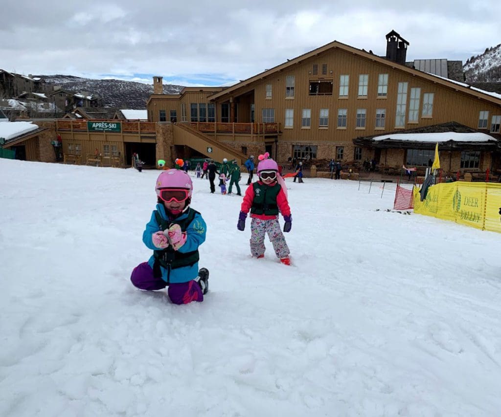 Two kids play in the snow outside of a resort in Park City, one of the best places for a White Christmas in the United States for families.