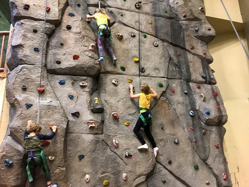Two kids climb along the rock wall at YMCA of the Rockies, one of the best weekend getaways near Denver for families.