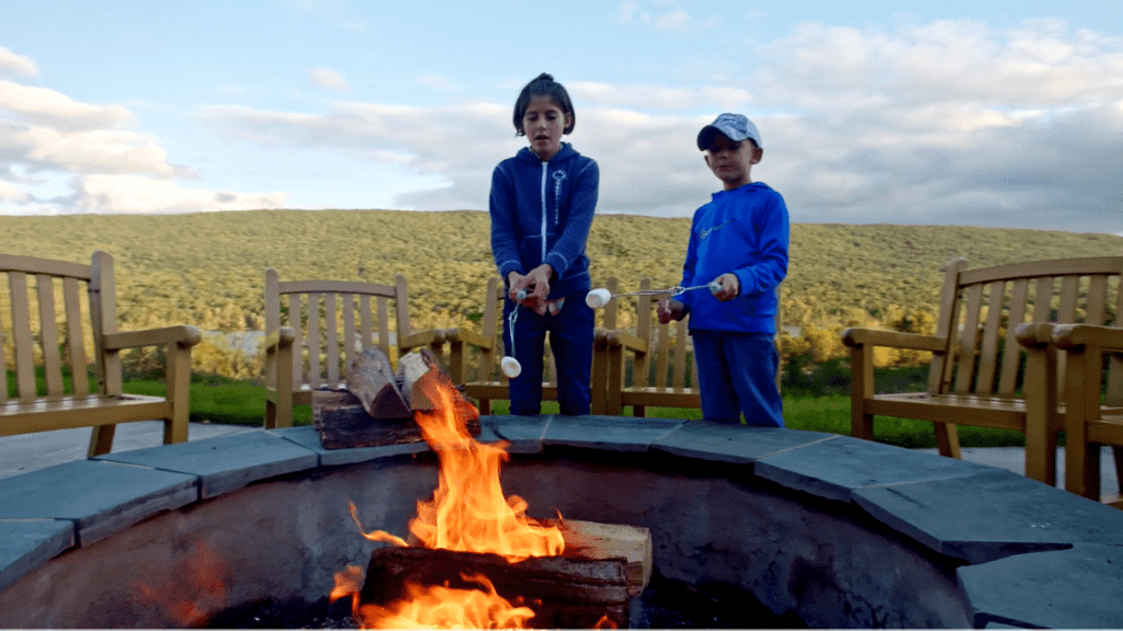 Two kids roast marshmallows at an outdoor fire pit at the The Nature Inn at Bald Eagle,