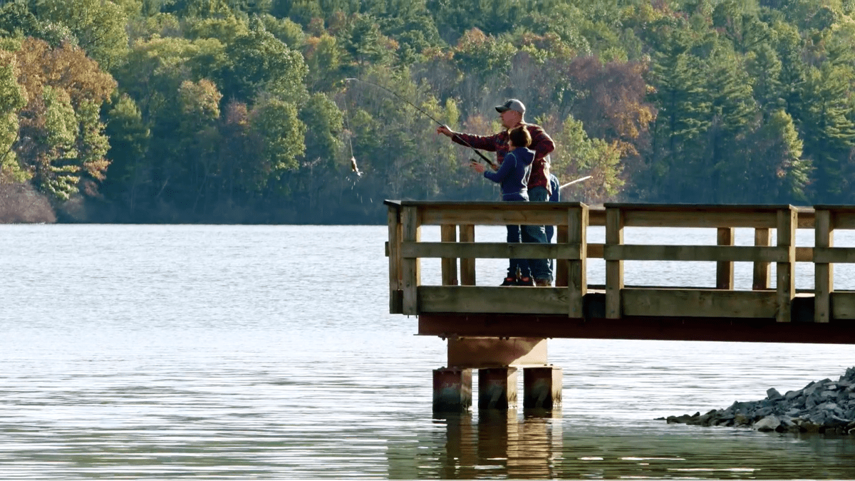 A man and his son fish from a dock at the The Nature Inn at Bald Eagle.