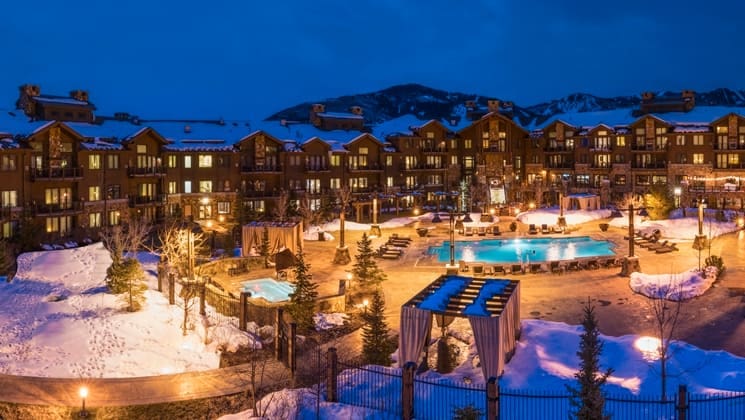 The exterior of the Waldorf Astoria Park City at night, featuring the building, pool, and grounds at one of the best Hilton Hotels in the United States for families.