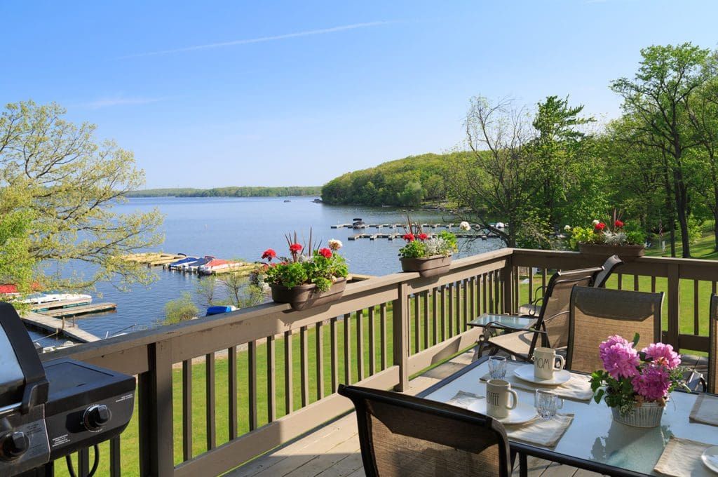 A deck with table and chairs overlooking the lake at the Silver Birches Resort.