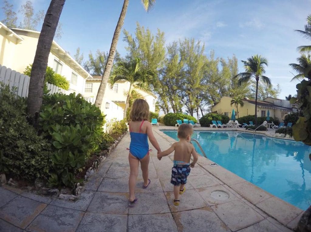 Two kids walk along the pool deck, near the pool, at the Sunrise Beach Villas.
