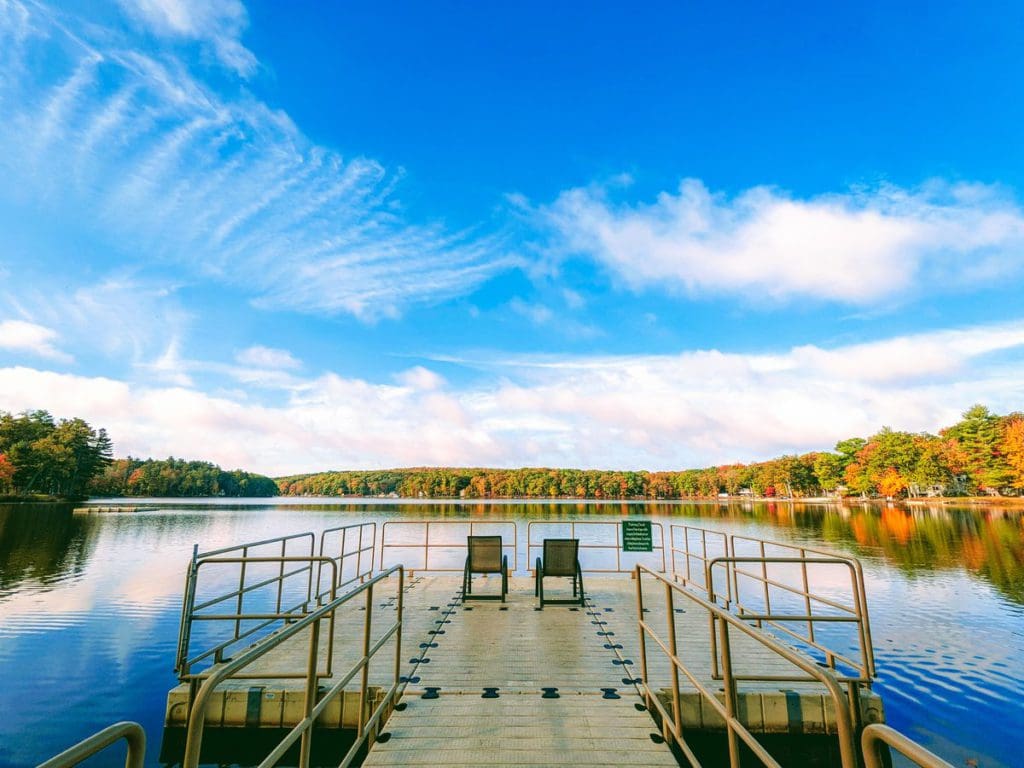 A dock at Woodloch Resort, featuring two empty chairs awaiting guests to enjoy the stunning fall view over the lake.