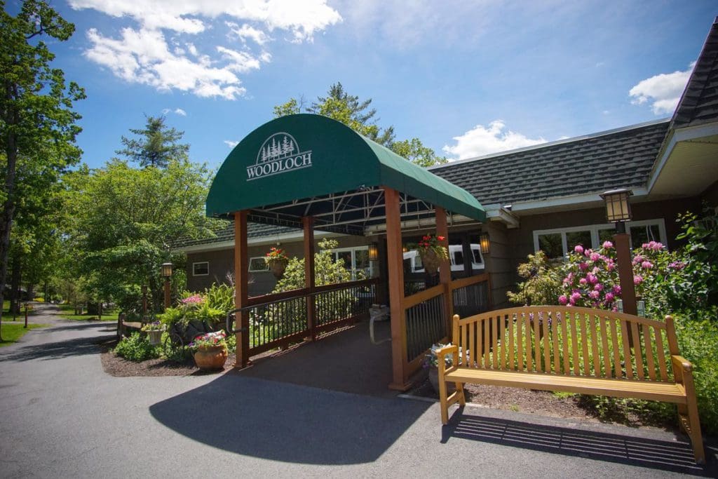 The entrance to Woodloch Resort, featuring an awning and lush gardening on both sides of the walkway.
