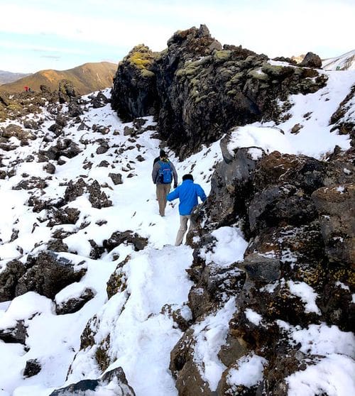 Two people hike along the snow in Landmannaluagar.