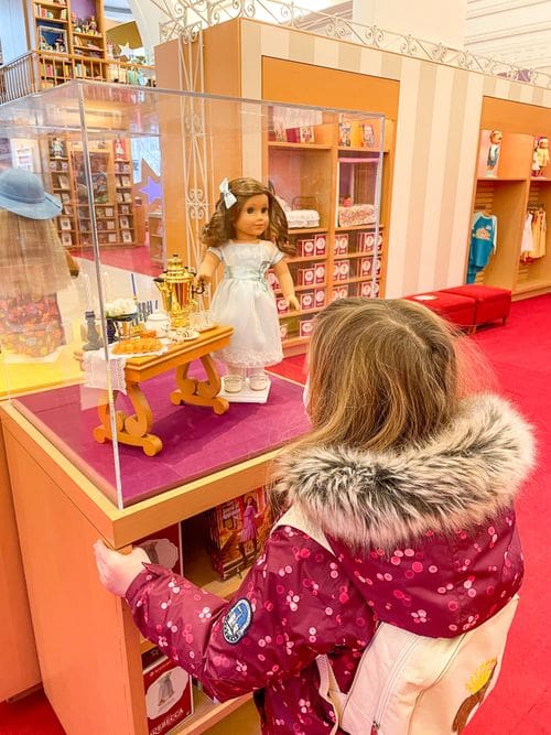 A young girl looks at a doll in a case at the American Girl Place, one of the best kids activities in Chicago.