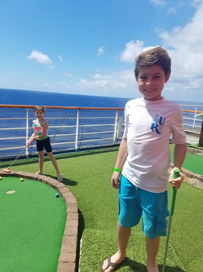 Two young kids play mini golf on a Carnival Cruise ship.