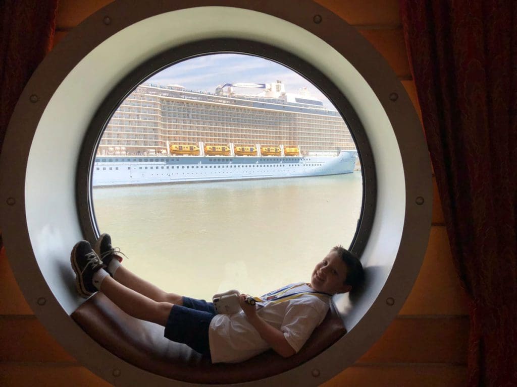 A young boy lays in a port window on a Disney Cruise.