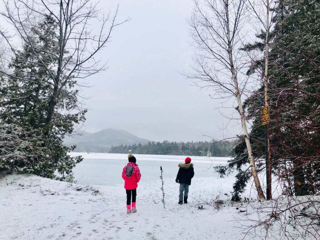 Two kids in full snow gear stand and look at Mirror Lake.