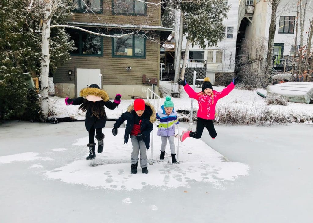 Several kids jump in the snow near their home rental in Lake Placid.