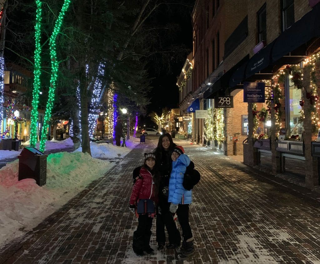 Two kids stand with their mom on a downtown Aspen street at night.