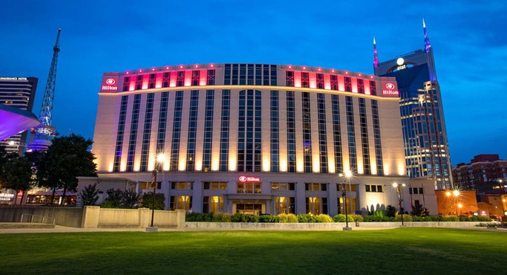 A view of the exterior of the Hilton Nashville Downtown at night, illuminated with many lights.