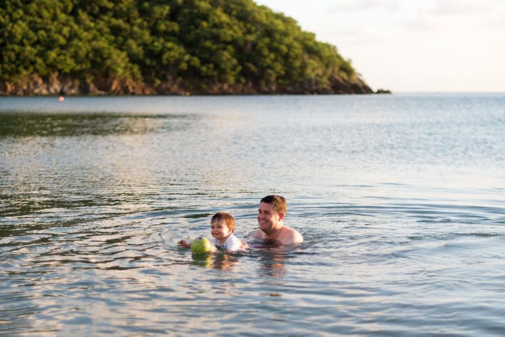 A dad and his young son swim in the water.