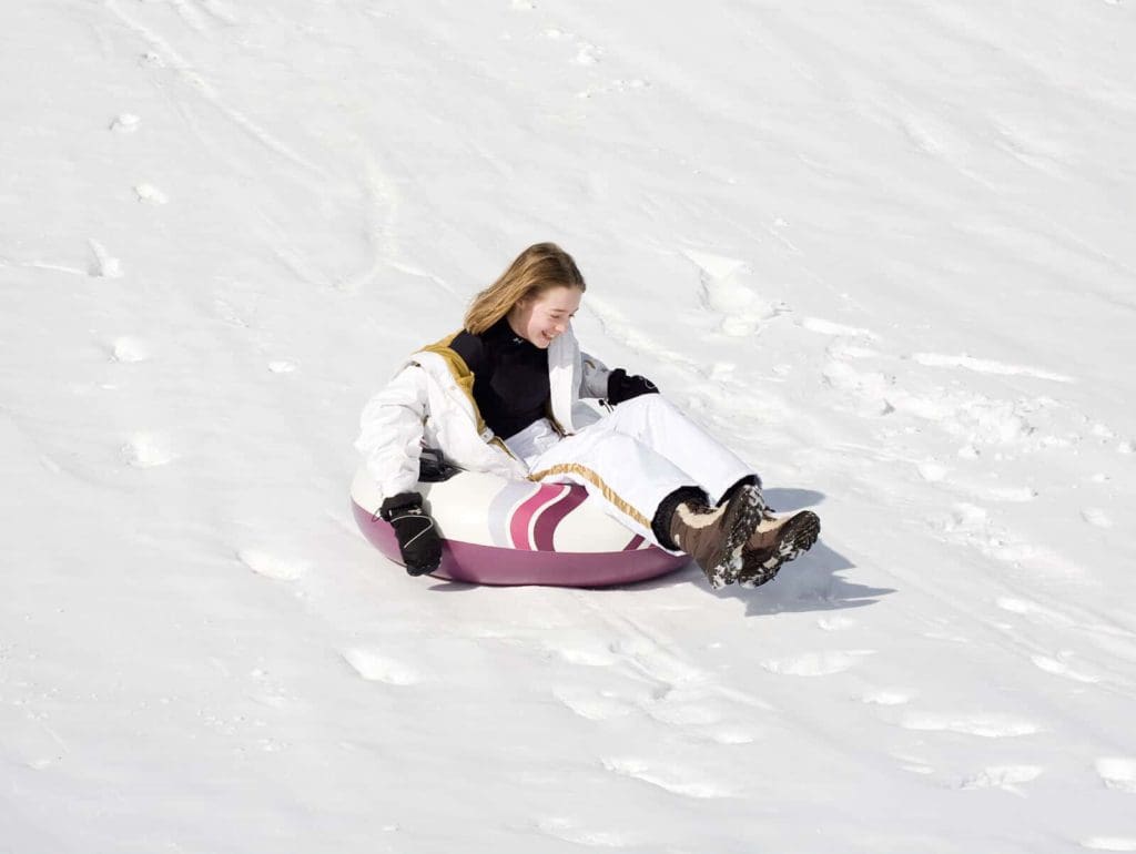 A young girl snow tubes down a snowy hill at Mohonk Mountain House, one of the best hotels with snow tubing near NYC for families.