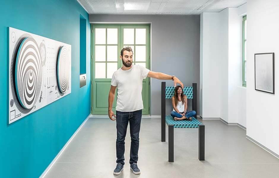 A man reached out to hold the head of a tiny woman sitting on a chair at the Museum of Illusions, one of the best indoor activities in New York City for kids.