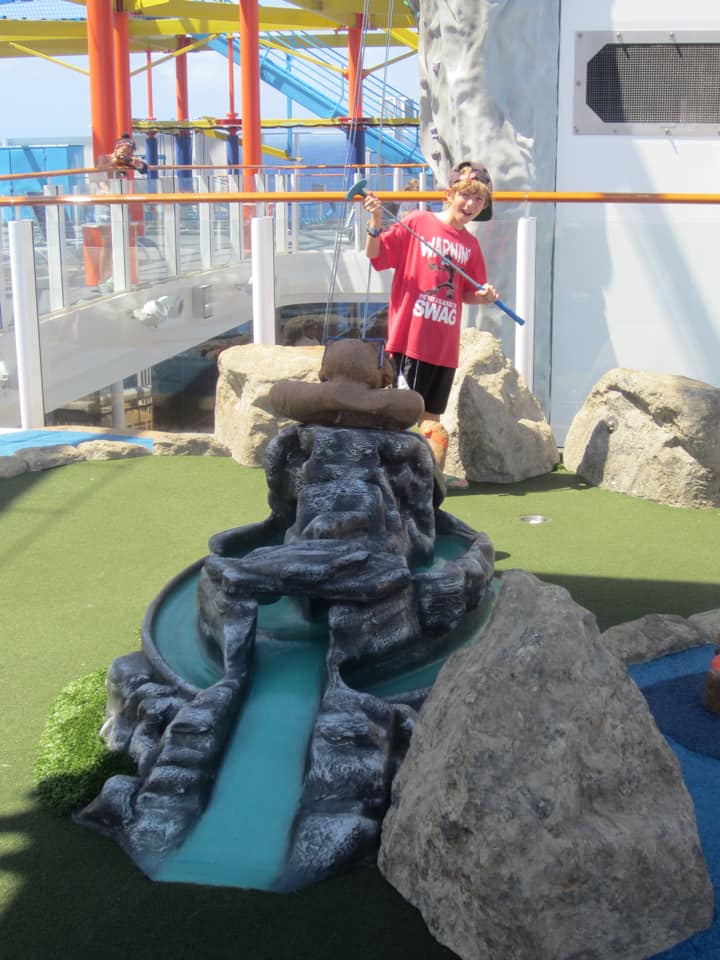 A young boy plays miniature golf aboard a Norwegian Cruise. 