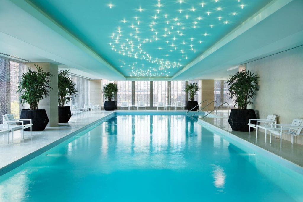 The luxury pool at The Langham, Chicago, featuring twinkling lights overhead and floor to ceiling windows.