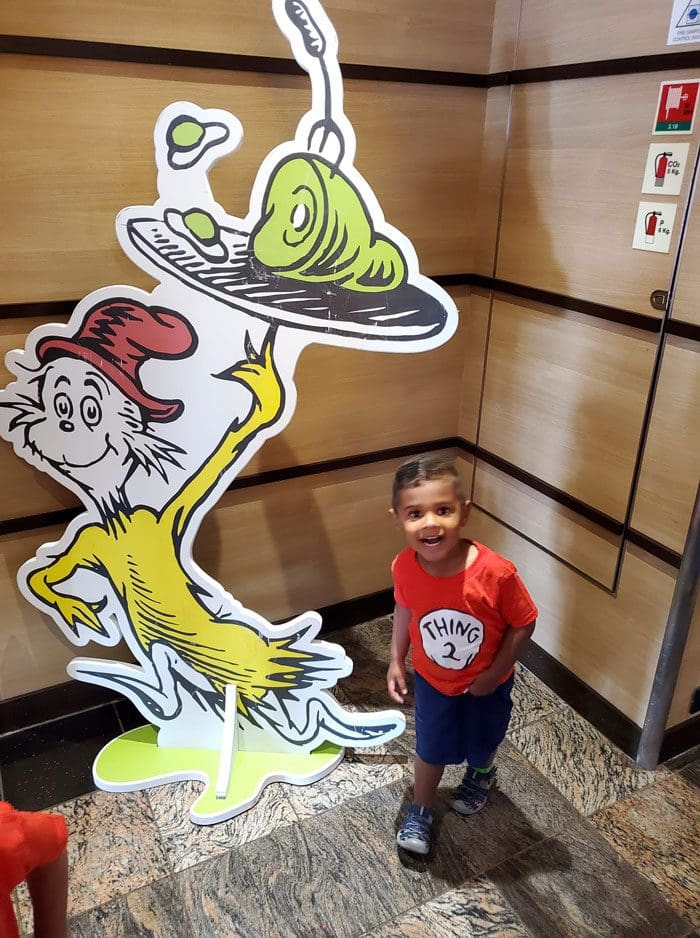 A young child stands next to a Dr. Seuss cutout on a family cruise.