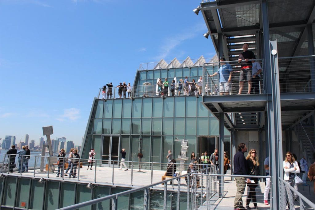 The exterior terrace of the The Whitney Museum of American Art, with several guests wandering about on a sunny day.